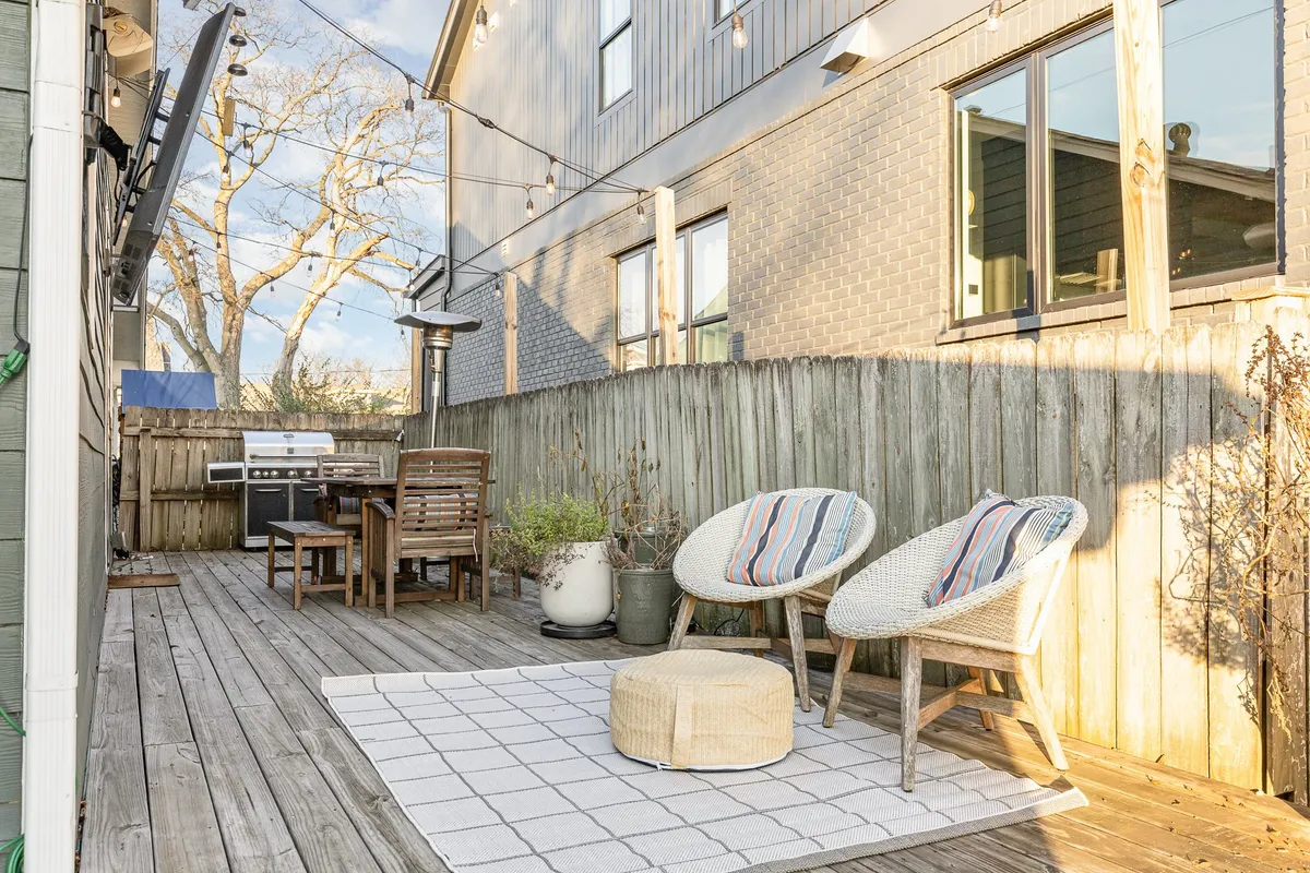 A welcoming outdoor dining set with lounge chairs, string lights creating a magical glow, and a grill nearby, setting the stage for al fresco dinners and social gatherings.