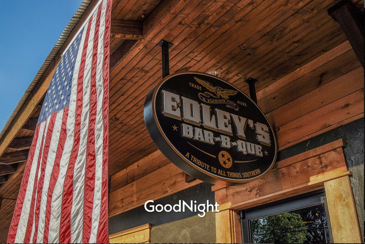 The exterior of Edley's Bar-B-Que, marked by its distinctive sign and the American flag, bustling with people enjoying meals and socializing. The image radiates a welcoming, community-oriented vibe, drawing attention to one of the area's beloved eateries.